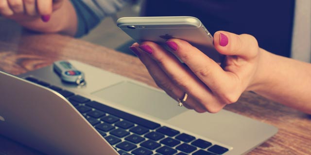 Laptop and a hand holding a mobile phone