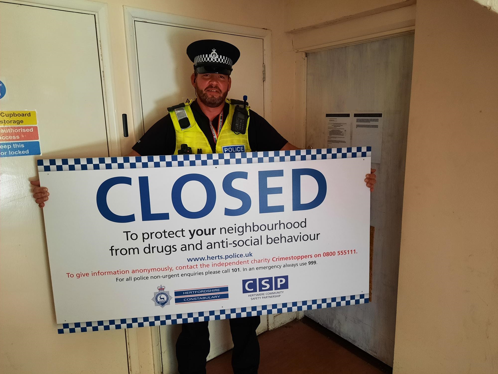 Image of officer holding a closure order sign outside an address