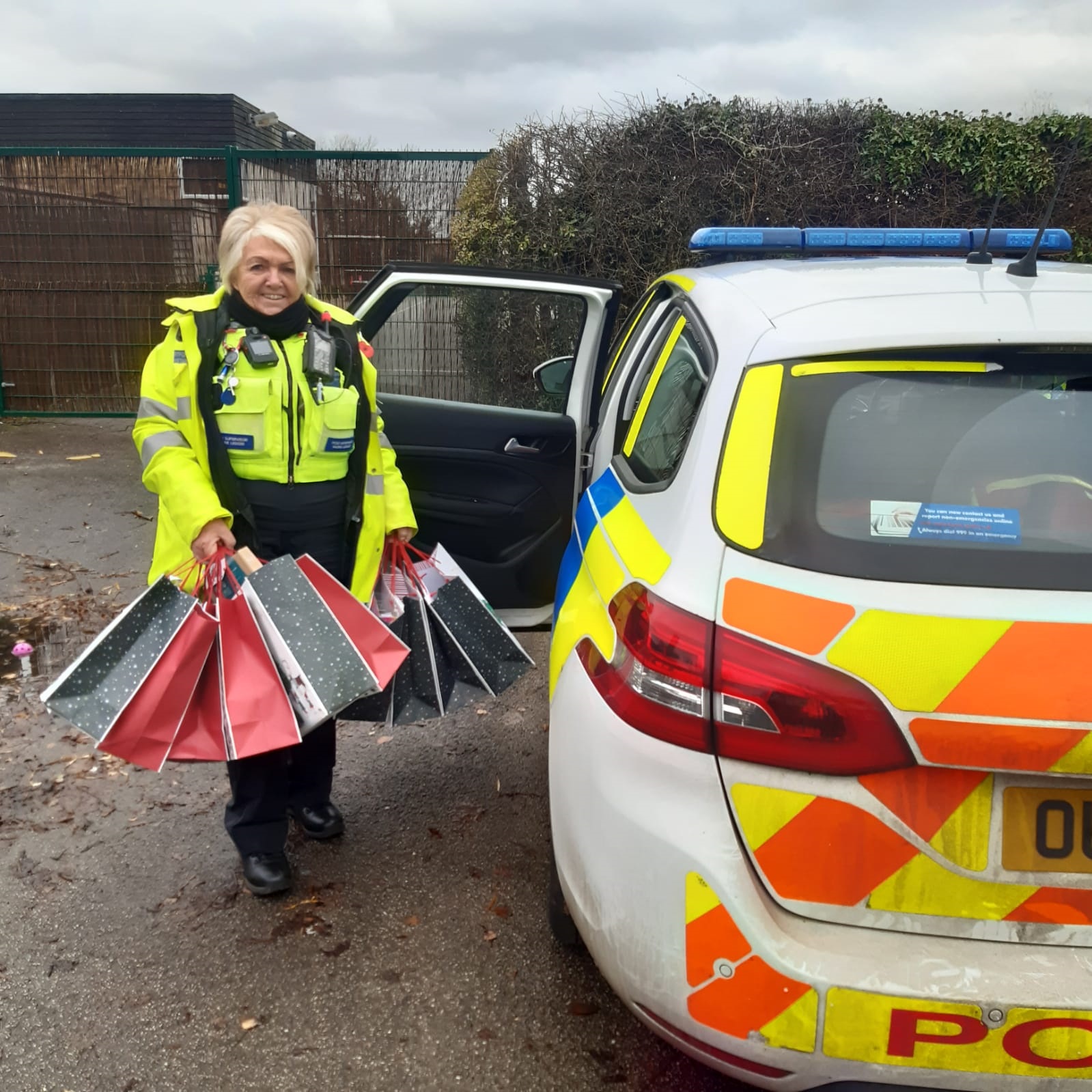 Image of PCSO by a police car with bags of presents