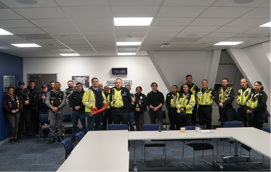 Police officers standing in a briefing room, lined up and looking at the camera
